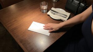 パパ活のお手当を白封筒でテーブルに置いて渡す場面