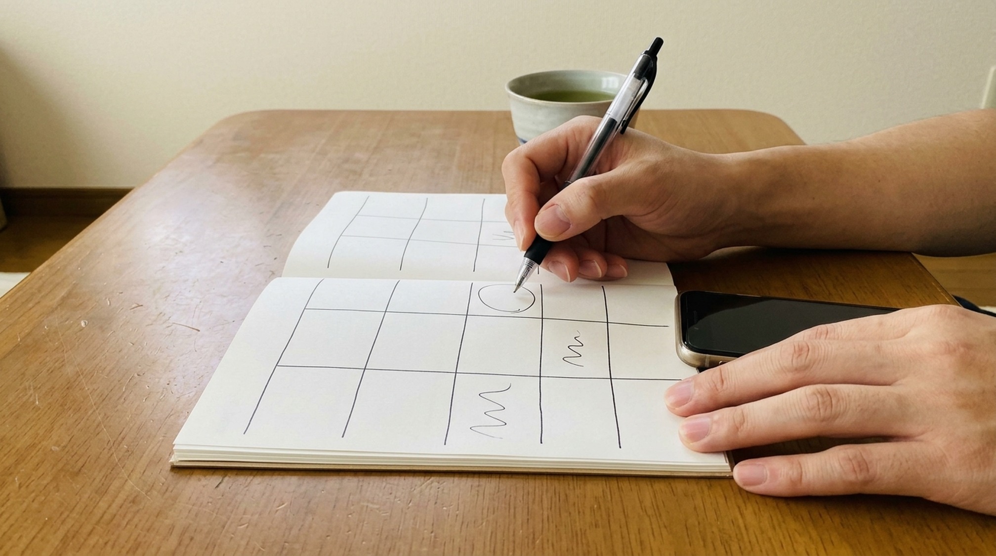 ペイターズとラブアンの比較の結論を手帳に書き込む手元